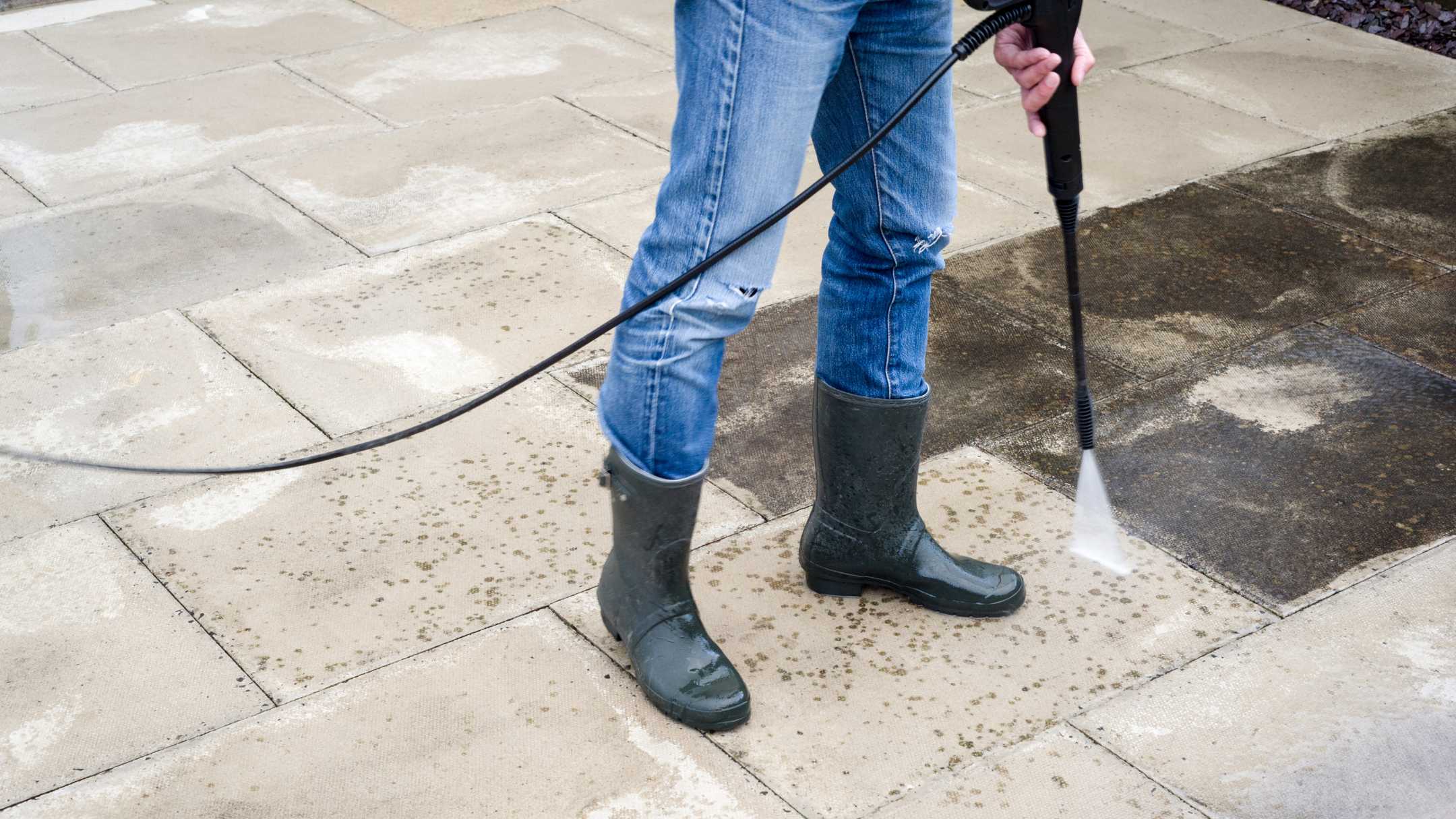 professional pressure washing concrete in black boots