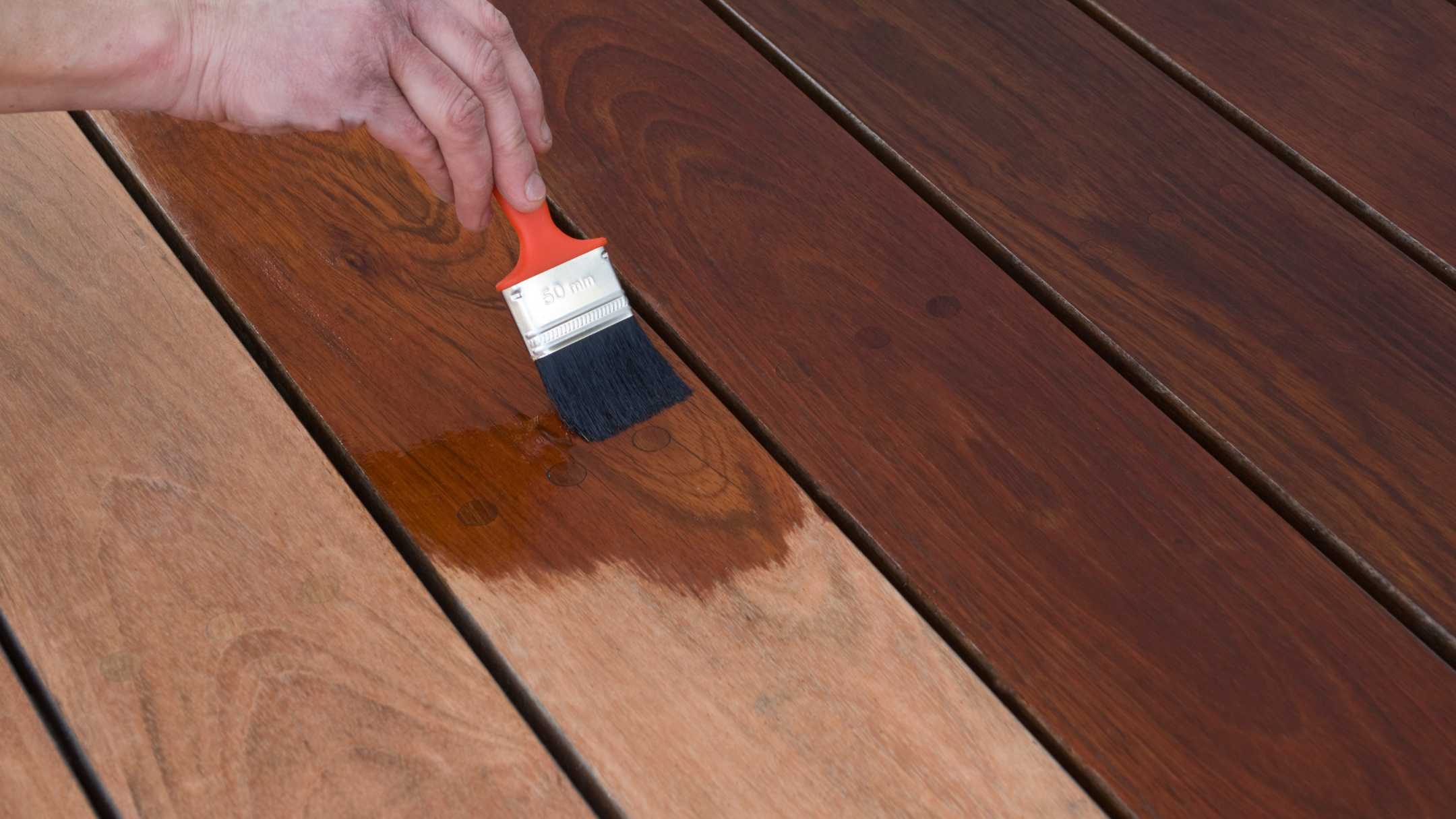 professional using red paint brush to stain wood